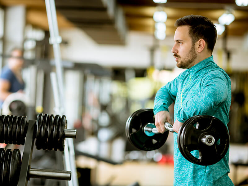 un homme à la salle de sport réalisant des épaulés jetées