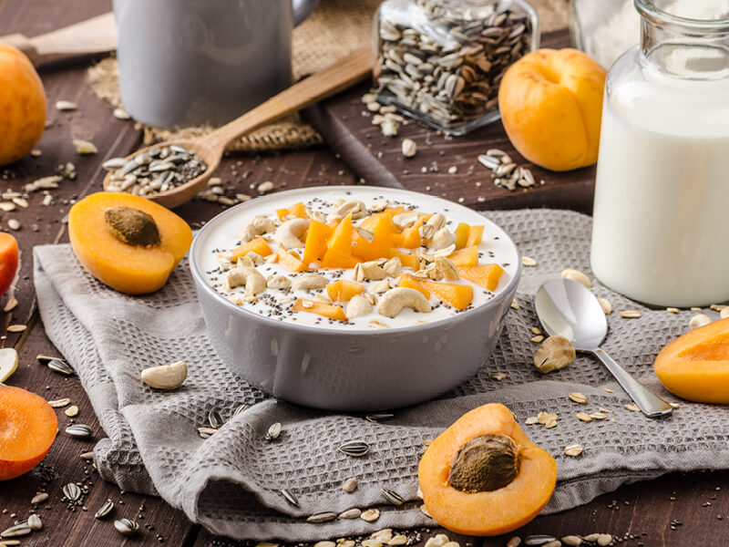 Recette de petit déjeuner healthy à l'abricot, au yaourt et aux noix pour illustrer un article sur les bienfaits de l'abricot