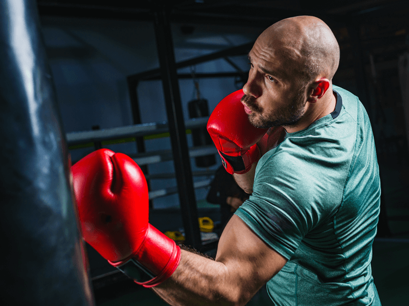 un homme avec des gants de boxe frappe dans un sac de frappe