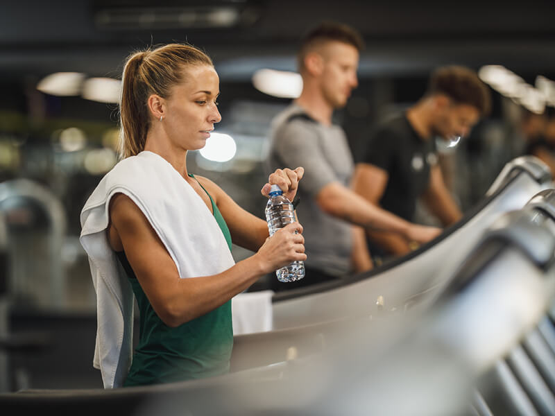 Une femme en train de s'hydrater à la salle de sport - S'hydrater à la salle de sport, les conseils de l'Appart Fitness