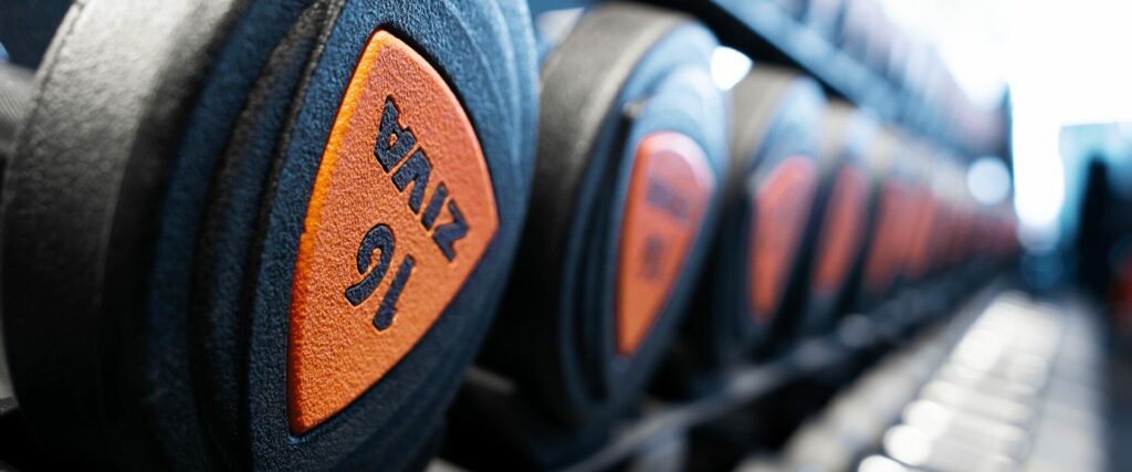 Stockage de poids libres noirs et oranges dans une salle de sport L'Appart Fitness