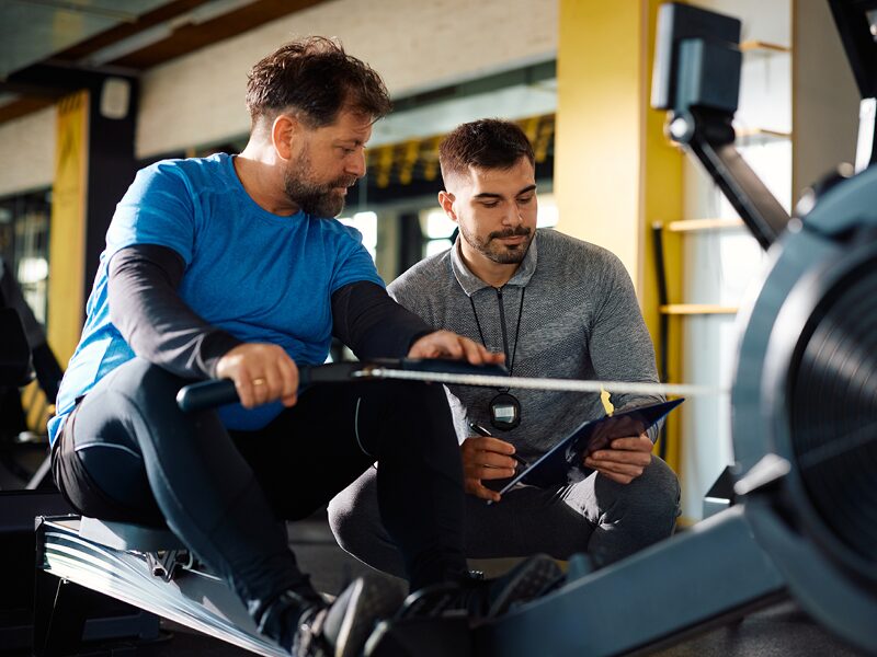 Adhérent L'Appart Fitness en train de faire du rameur lors d'une séance de coaching personnalisé dans une salle de sport