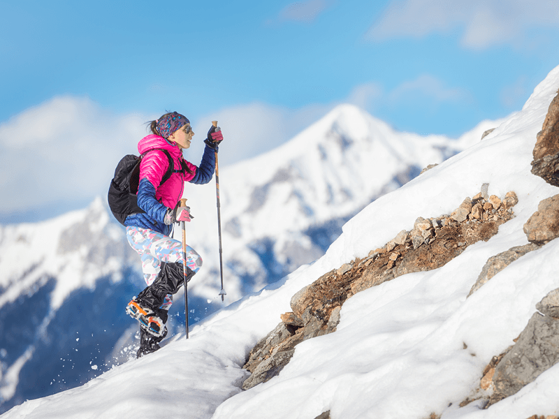 Une femme en pleine ascension d'une montagne en hiver