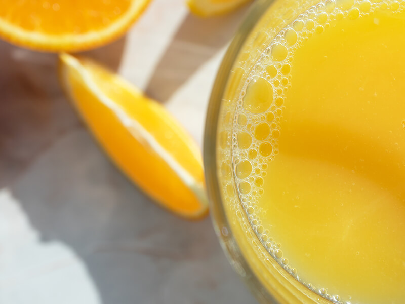 Un jus d'orange et un quartier d'Orange pour illustrer un article sur la vitamine C