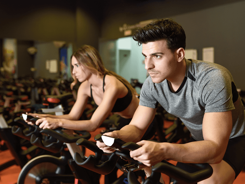 Un homme et une femme lors d'une séance de RPM dans une salle de sport L'Appart Fitness