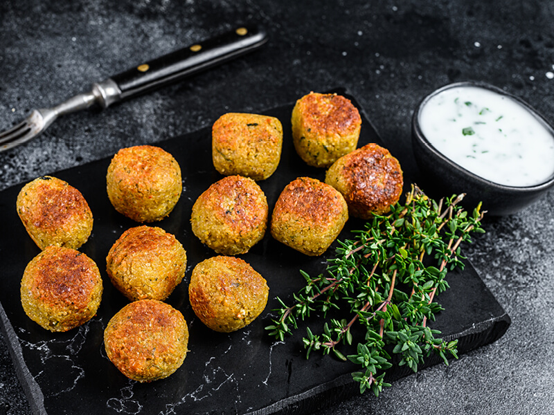 Boulettes de poulet sur une ardoise noire avec une sauce yaourt en accompagnement