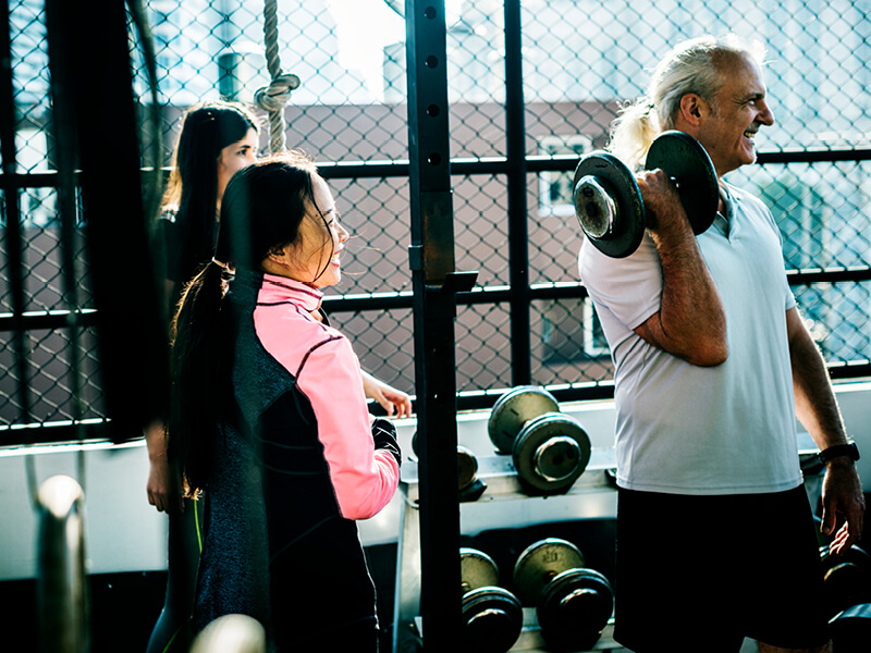 Visuel montrant trois personnes soulevant des altères en extérieur, illustrant un article sur le vocabulaire du fitness