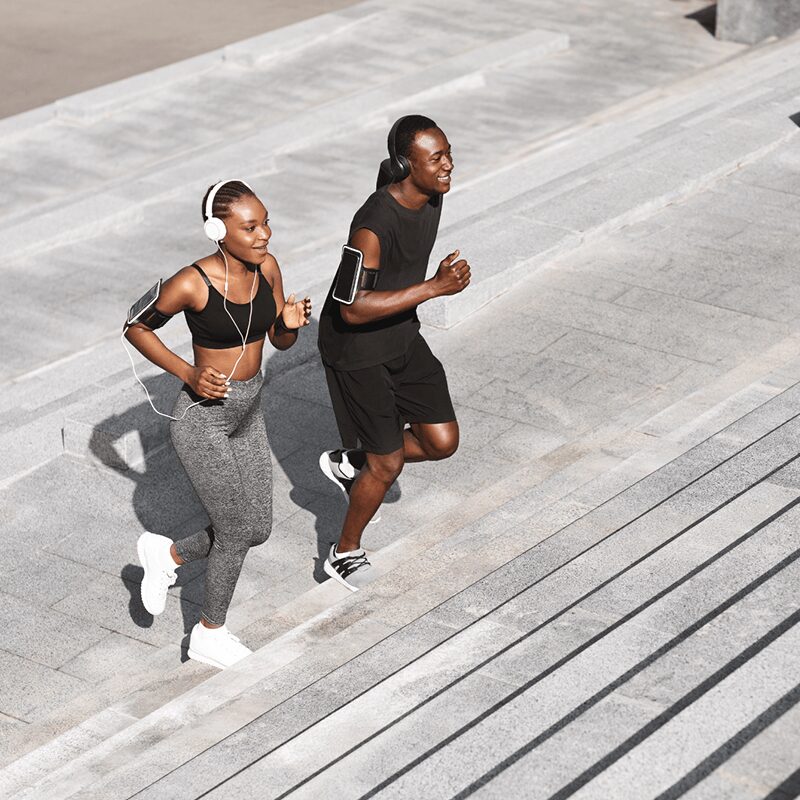 Deux personnes courant sur des escaliers en extérieur, illustrant comment courir son premier 10km avec le soutien de L'Appart Fitness.