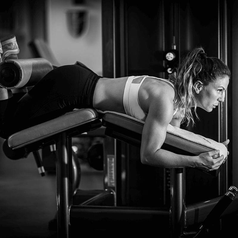 Femme réalisant un leg curl, un des exercices bas du corps recommandés par L'Appart Fitness pour renforcer les ischio-jambiers.