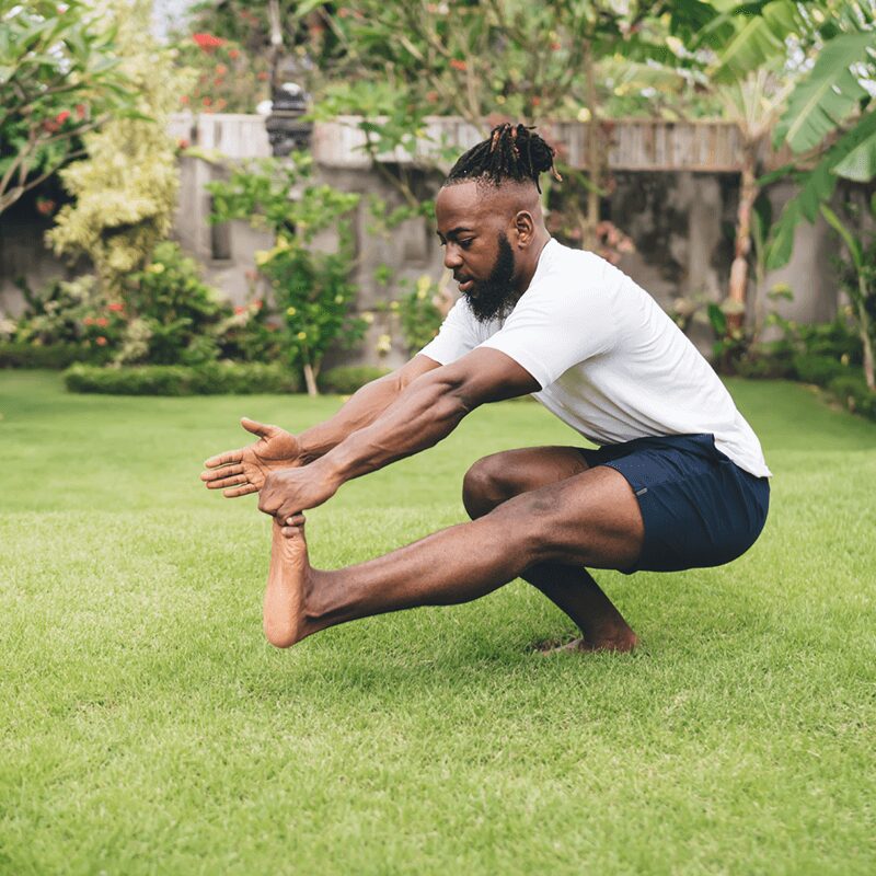 Un homme pratiquant le squat pistol en extérieur, un exercice bas du corps exigeant proposé par L'Appart Fitness pour travailler l'équilibre et la force.