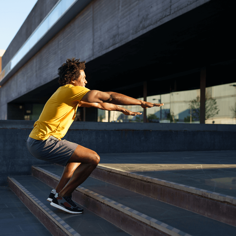 Un homme pratiquant des squats sautés en extérieur, un exercice bas du corps recommandé par L'Appart Fitness pour augmenter l'explosivité et la force.