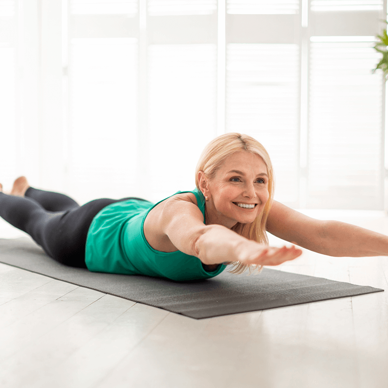 une femme réalisant un superman, un exercice parfait pour travailler les fessiers et les muscles du bas du dos.