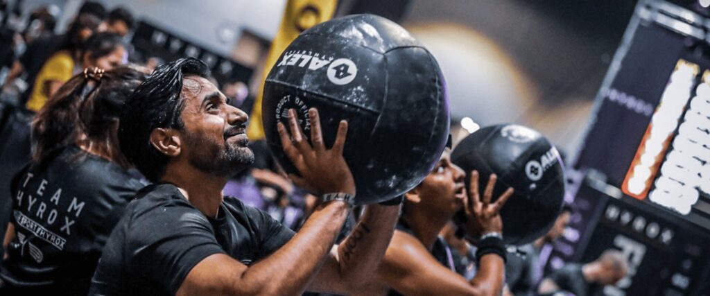 Épreuve wall balls lors d'un entraînement Hyrox à L'Appart Fitness, ambiance compétitive et déterminée.