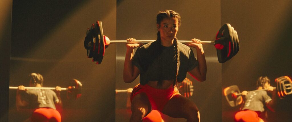 Une femme sportive en plein entraînement de squats dans un programme musculation à L’Appart Fitness, illustrant l’intensité des cours Bodypump et Cross training.