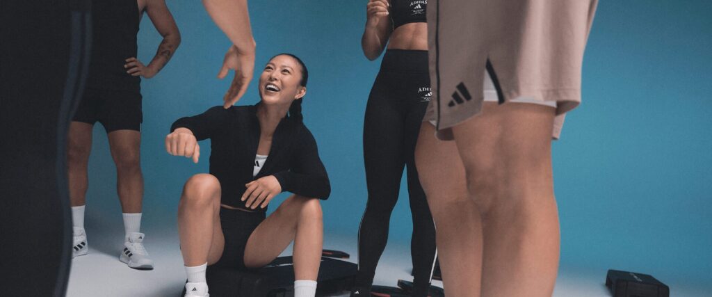 Adhérente L’Appart Fitness souriante pendant une séance Small Group, entourée du coach et du groupe dans une ambiance dynamique et bienveillante.